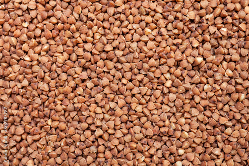 Uncooked, brown buckwheat grains background. Dry buckwheat grains. Top view Uncooked, brown buckwheat grains background. Dry buckwheat grains. Top view