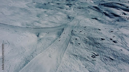 People going downhill on white ski slope, aerial