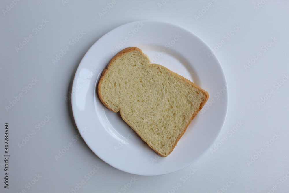 One slice of white bread, on white plate, isolated on white background, flat lay or top view