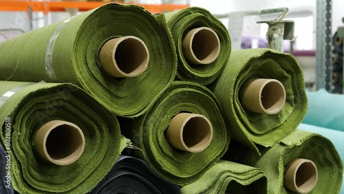 large rolls of new green fabric in weaving factory warehouse close-up, textile