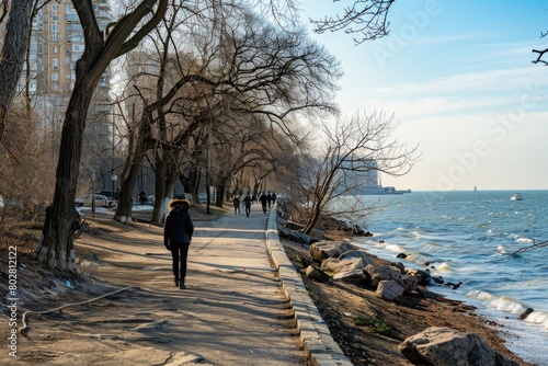 A person walking down a sidewalk next to the water. Suitable for travel or lifestyle themes