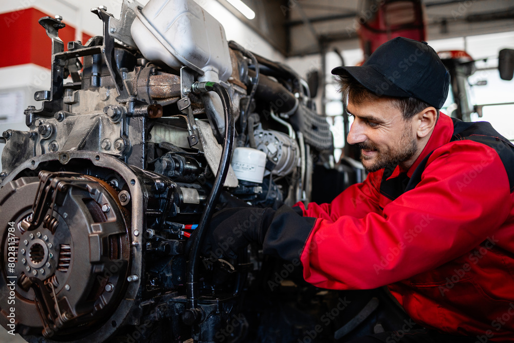 Mechanic servicing tractor engine in workshop.