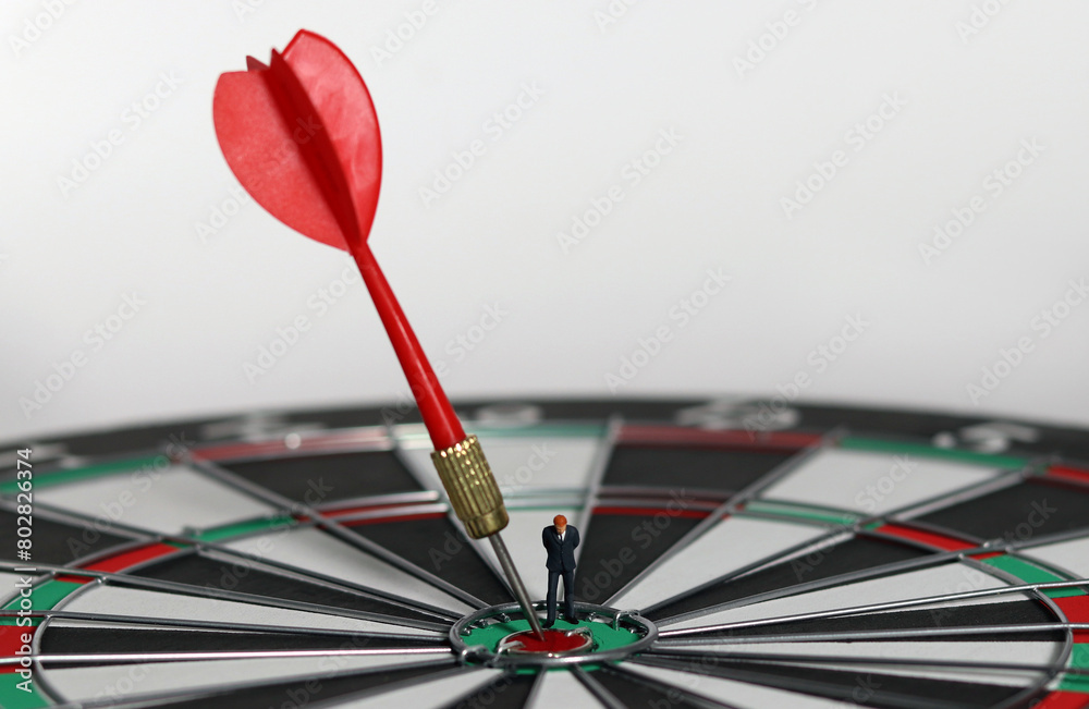 The red dart arrow in the middle of the dart paper is the goal of the business. An entrepreneur looking at arrows on a dartboard. Concept of business marketing plans and objectives. The red dart arrow in the middle of the dart paper is the goal of the business. An entrepreneur looking at arrows on a dartboard. Concept of business marketing plans and objectives.