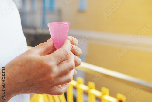 Pink Color Silicone Menstrual Cup In the Femmale Hands.  Comfortable Reusable Period Cup, Tampon and Pad Alternative - Feminine Menstruation. Gynecologist recommended. photo