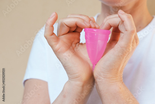 Pink Color Silicone Menstrual Cup In the Femmale Hands.  Comfortable Reusable Period Cup, Tampon and Pad Alternative - Feminine Menstruation. Gynecologist recommended. photo