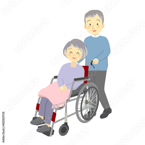 仲良しシニア夫婦が車いすで散歩する様子（妻の車椅子を押す高齢男性）
