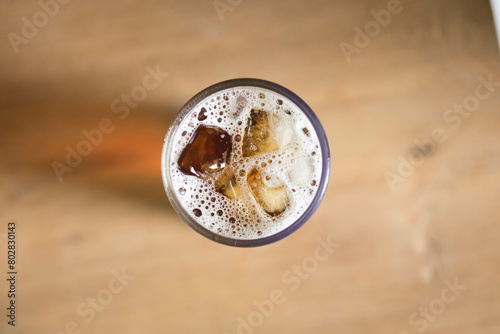 Americano ice coffee in a glass, isolated on brown wooden table, with clipping path, top view, flat lay. photo