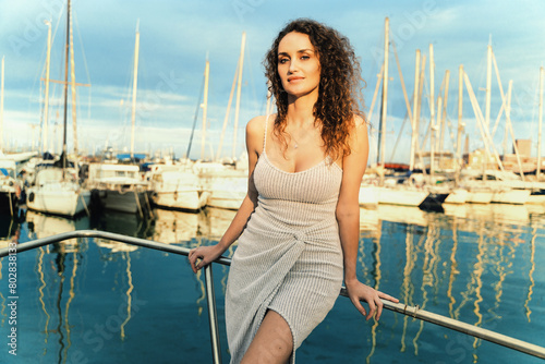 Stylish woman - posing on yacht with a marina backdrop, wearing a chic summer dress - elegance, leisure, fashionable. (ID: 802838133)
