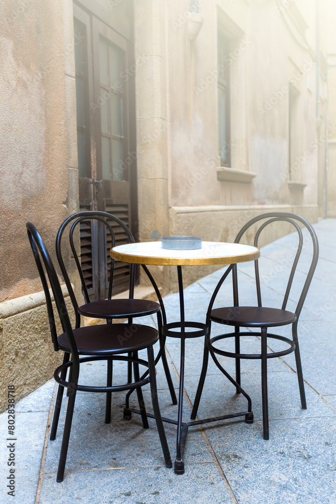 Obraz premium Tables of a cafe on the old city on soft sunlight