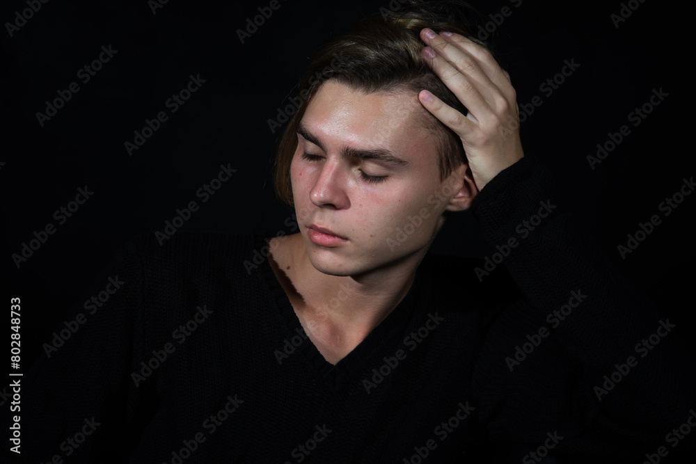 A young attractive guy is resting. Black background.