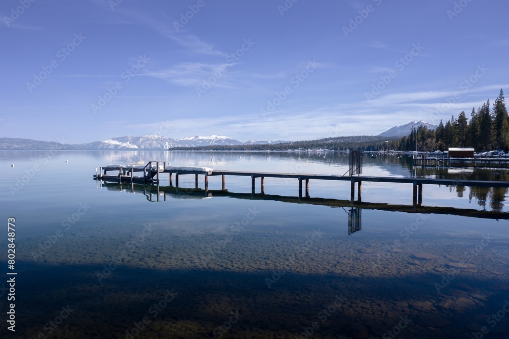Pier, mountains with snow on calm Lake Tahoe, Homewood, California, United States of America.