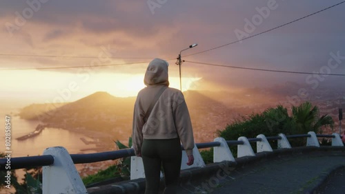 Girl in Hood Walking, Amazing Cloudy Sunset over City in the Background photo