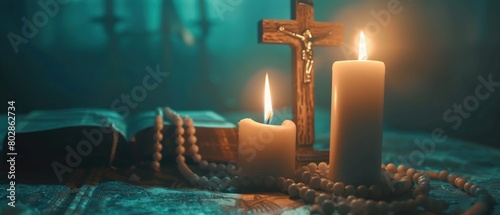 Religious still life with cross, candles, bible, and rosary beads on a wooden surface with a blurred background. photo
