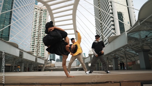 Group of professional street dancer cheer up while asian hipster perform freestyle footstep at city surrounded by people with low angle camera. Break dance concept. Outdoor sport 2024. Sprightly.
