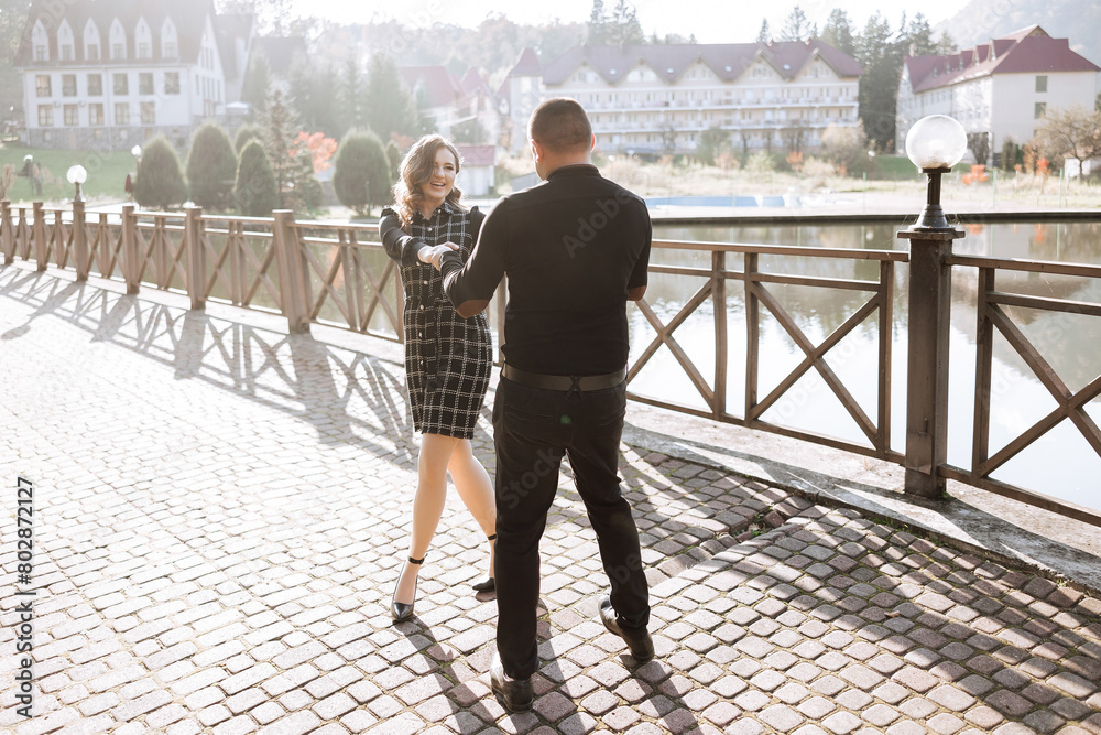 Obraz premium A man and a woman are dancing on a brick walkway. The man is wearing a black shirt and the woman is wearing a black dress
