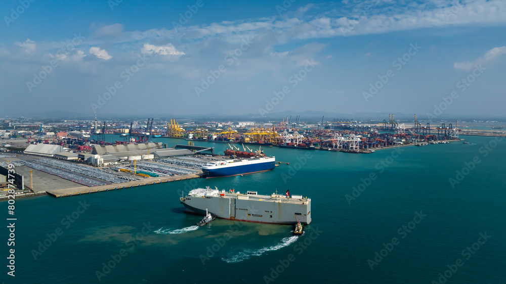 tugboat pushing Roll-on Roll-of ship into the port. Automotive container carriers floating in sea, new car lined up in the port for import and export to dealership for sale,