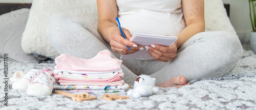 Fotografie A pregnant woman collects baby things. Selective focus.