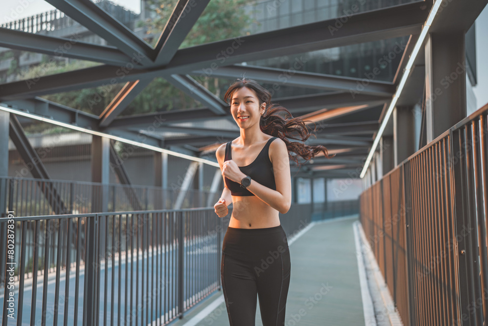 Young asian woman runner is training in the summer sunset within a city, The athlete fit and firm girl exercising by jogging workout sport outdoor for her healthy wellness.