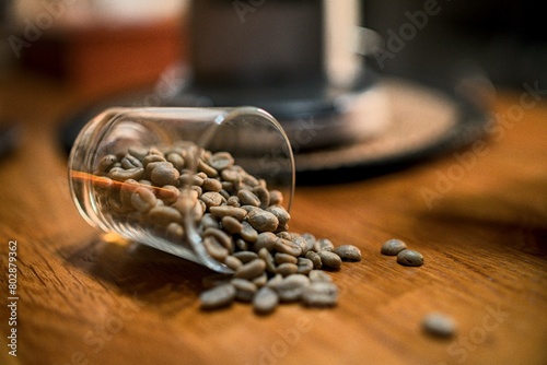 Green fresh coffee beans laying on table falling from glass container for torrefactor photo