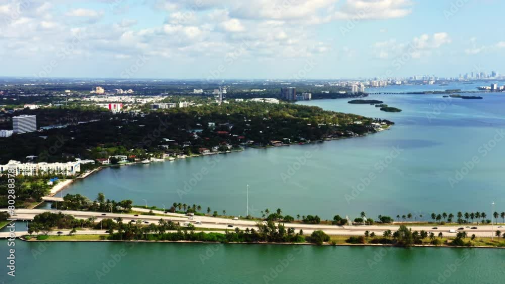 4k drone flies along the road with cars driving on a freeway on a sunny day in the city of Miami. Aerial top veiw footage from above a busy road with green palm trees overlooking Biscayne Bay. USA 4k drone flies along the road with cars driving on a freeway on a sunny day in the city of Miami. Aerial top veiw footage from above a busy road with green palm trees overlooking Biscayne Bay. USA