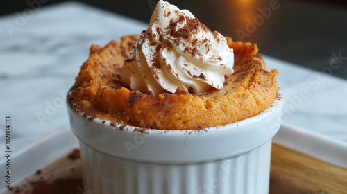 Delicious jamaican sweet potato pudding with a whipped cream swirl and a sprinkle of cinnamon, presented in a white ramekin