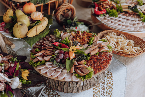 A table is covered with a variety of food, including meats, fruits, and vegetables. The table is set for a party or gathering, and the food is arranged in a way that is visually appealing and inviting
