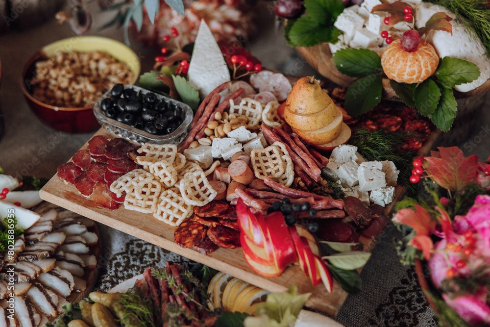 A table full of food with a variety of meats, fruits, and vegetables. The table is set for a party or gathering A table full of food with a variety of meats, fruits, and vegetables. The table is set for a party or gathering