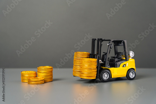 A forklift brings cash coins. Attracting investments. Brings profit and earnings. Injecting funds into the economy and industrial sector. Subsidization. Advantageous loans for industry and production. photo