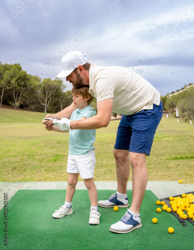 Dad teaches his little son to play golf.