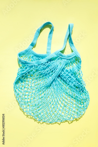 Reusable blue mesh bag on a yellow background in sunny daylight. Mesh shopping bags. Sustainable use concept