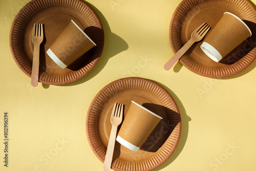 A set of paper utensils and wooden cutlery on a yellow background. Eco friendly, zero waste concept. Top view