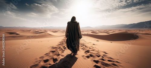 Rear view of a traveller arabic man walking in the desert among the sand dunes.Panoramic desert horizion view at daylight. © bagotaj