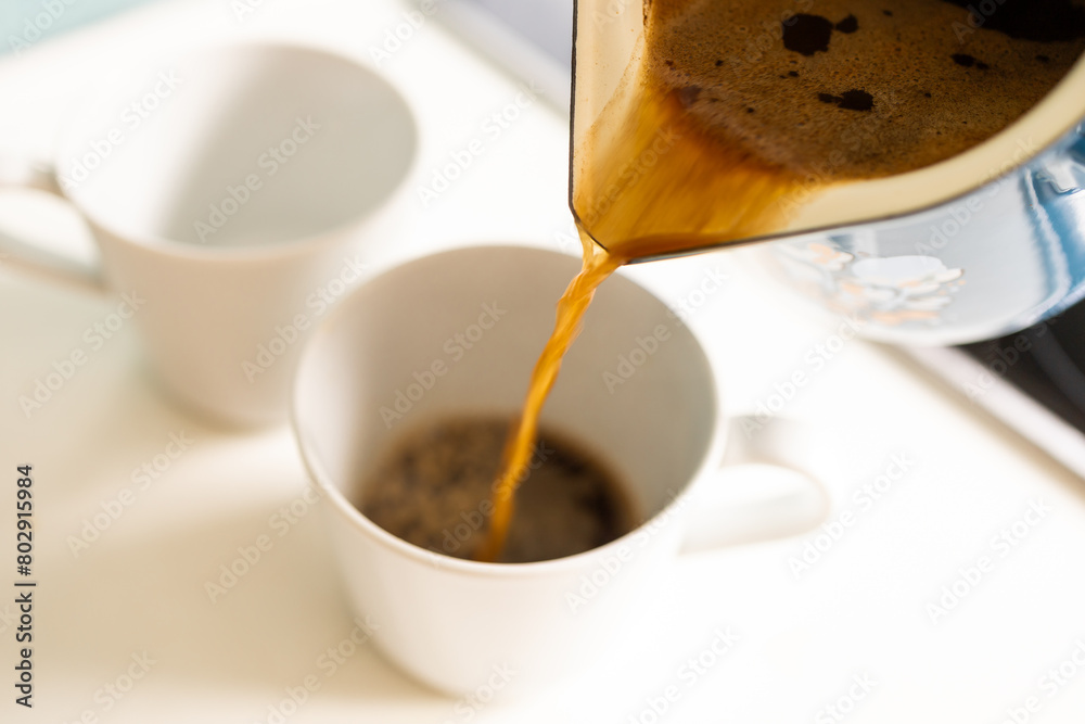 Pour freshly brewed coffee from the cup pot into a mug.