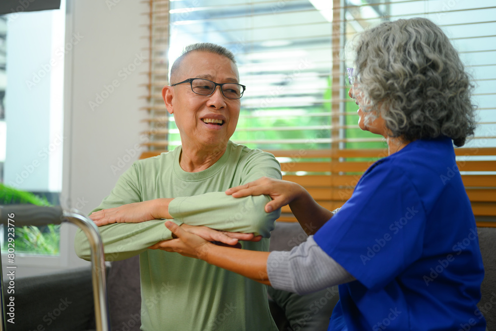 Fototapeta premium Senior male patient doing physical exercises with his physiotherapist at home. Rehabilitation and healthcare concept