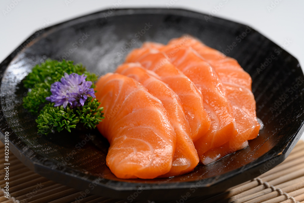 Close up sliced salmon with parsley leaf in black plate. Japanese food style
