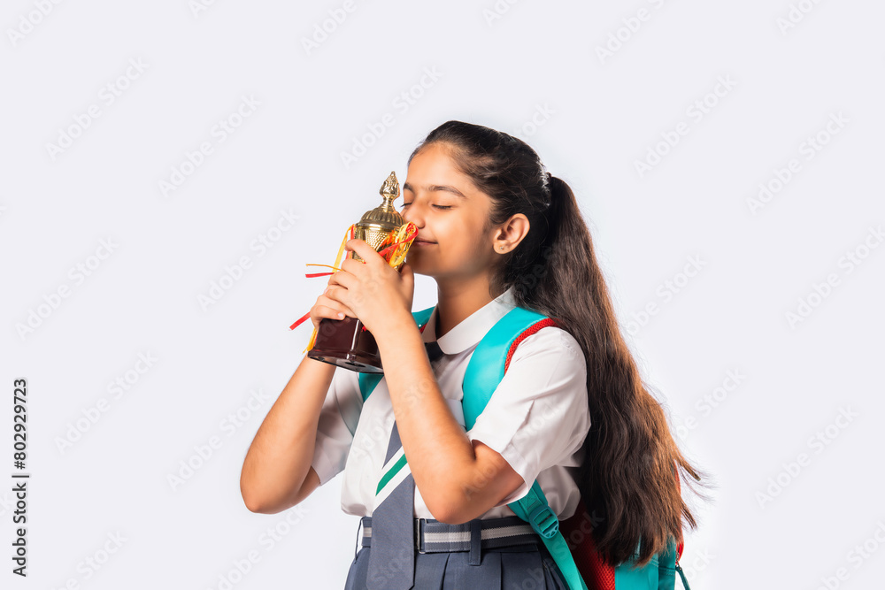 Excited Indian asian girl student in school uniform holding victory trophy in hand isolated on white background, Studio shot. Excited Indian asian girl student in school uniform holding victory trophy in hand isolated on white background, Studio shot.