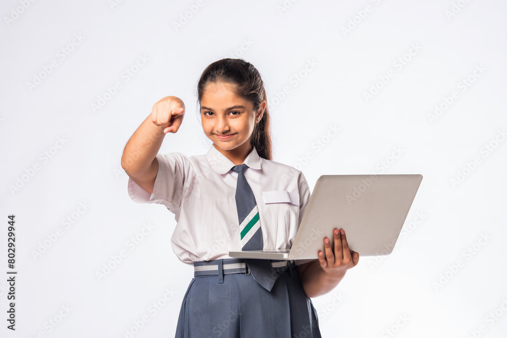 Indian asian schoolgirl in school uniform holding laptop isolated on white background Indian asian schoolgirl in school uniform holding laptop isolated on white background