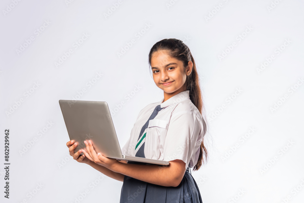 Indian asian schoolgirl in school uniform holding laptop isolated on white background Indian asian schoolgirl in school uniform holding laptop isolated on white background