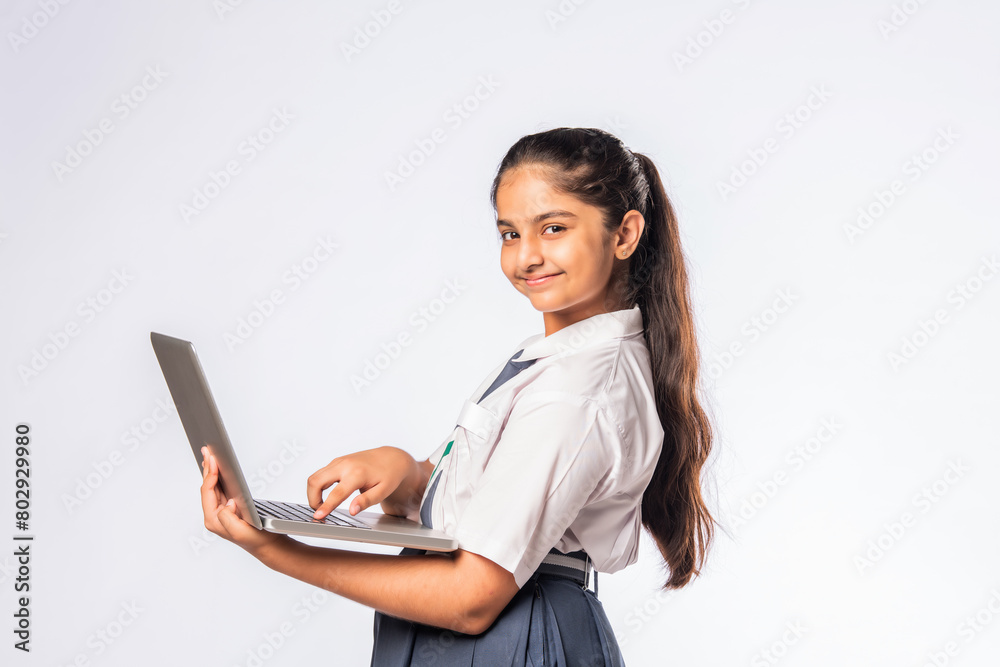 Indian asian schoolgirl in school uniform holding laptop isolated on white background Indian asian schoolgirl in school uniform holding laptop isolated on white background