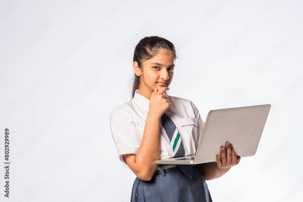 Indian asian schoolgirl in school uniform holding laptop isolated on white background Indian asian schoolgirl in school uniform holding laptop isolated on white background