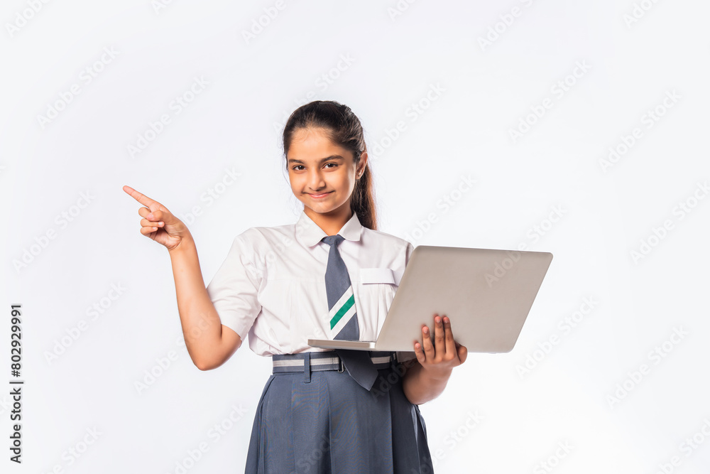 Indian asian schoolgirl in school uniform holding laptop isolated on white background Indian asian schoolgirl in school uniform holding laptop isolated on white background