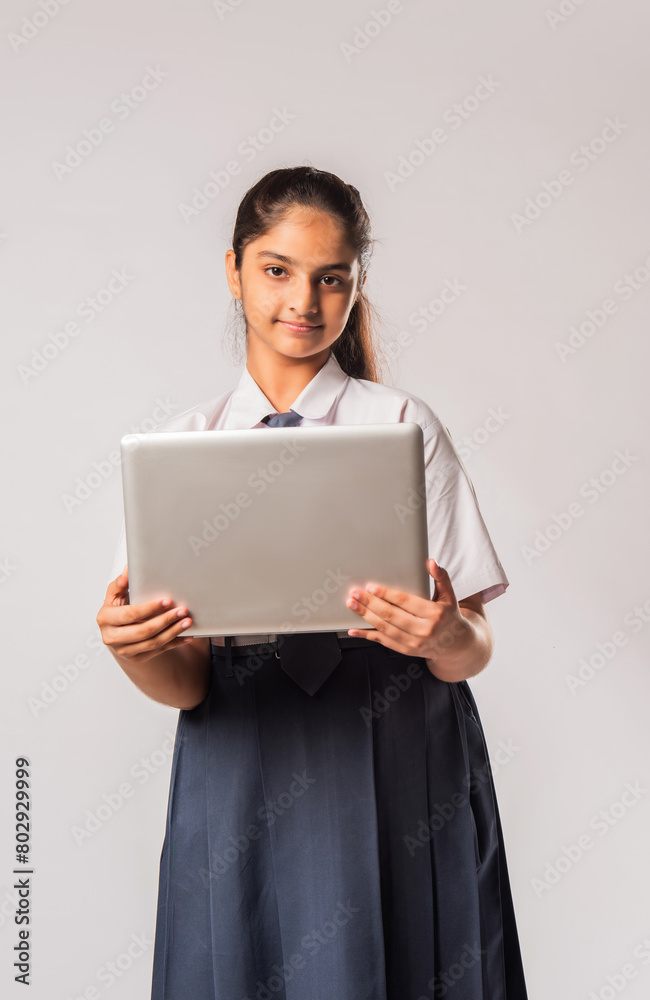 Indian asian schoolgirl in school uniform holding laptop isolated on white background Indian asian schoolgirl in school uniform holding laptop isolated on white background