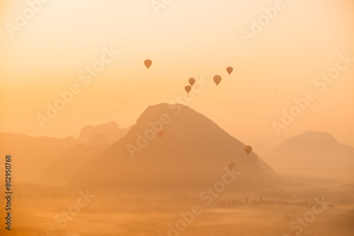 hot air balloons rising at golden sunrise in the mountain valley in Vang Vieng, the adventure capital of Laos photo