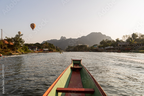 boat going down the river towards mountains and hot air balloon in Vang Vieng, the adventure capital of Laos