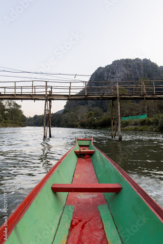 boat on the river going under bamboo bridge in Vang Vieng, the adventure capital of Laos