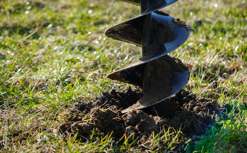 Drilling the ground with rig machine. The man drills the hole in land. Borering for the fence installation. Bore tool. Handy equipment. Portable manual earth auger for planting bushes and trees