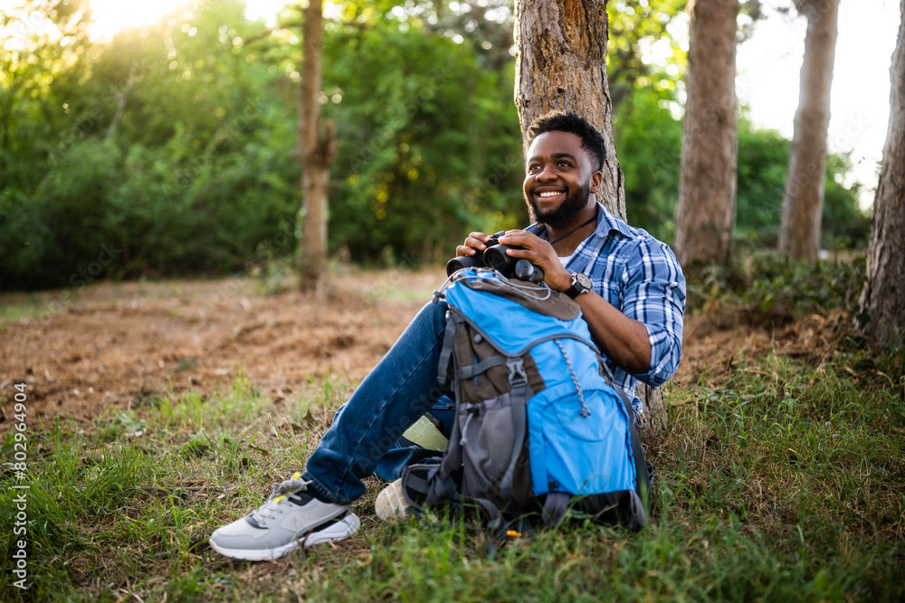Young hiker using binoculars while resting in nature. Young hiker using binoculars while resting in nature.