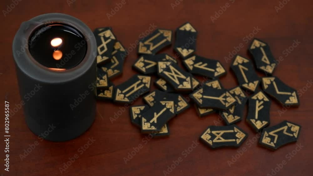 Burning black witch candle and black runes on wooden table. Burning black witch candle and black runes on wooden table.