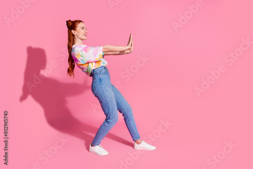 Full size photo of positive girl dressed colorful blouse jeans hold palms say stop look empty space isolated on pink color background © deagreez