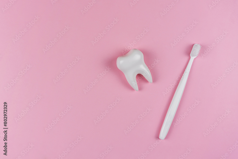 A healthy white tooth and toothbrush on a pink background. The concept of a dental clinic, dentistry, health care, oral care. Oral hygiene, professional teeth cleaning. Copyspace text A healthy white tooth and toothbrush on a pink background. The concept of a dental clinic, dentistry, health care, oral care. Oral hygiene, professional teeth cleaning. Copyspace text